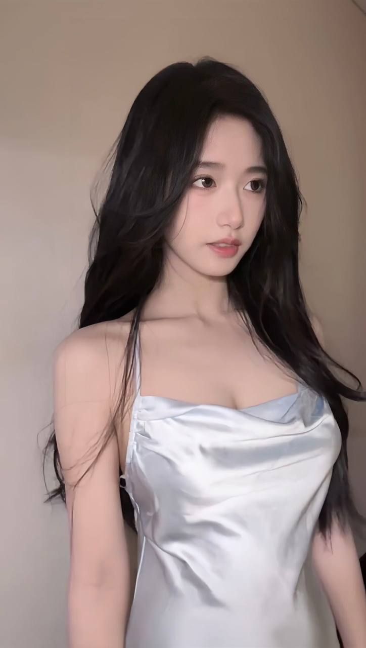 Woman with long black hair wearing a light blue satin cowl neck dress