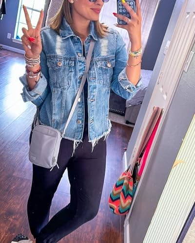 Woman in a denim jacket and black leggings taking a mirror selfie