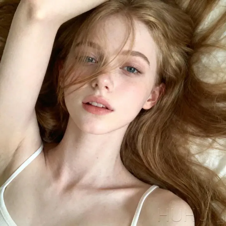 Woman with long red hair and blue eyes wearing a white top
