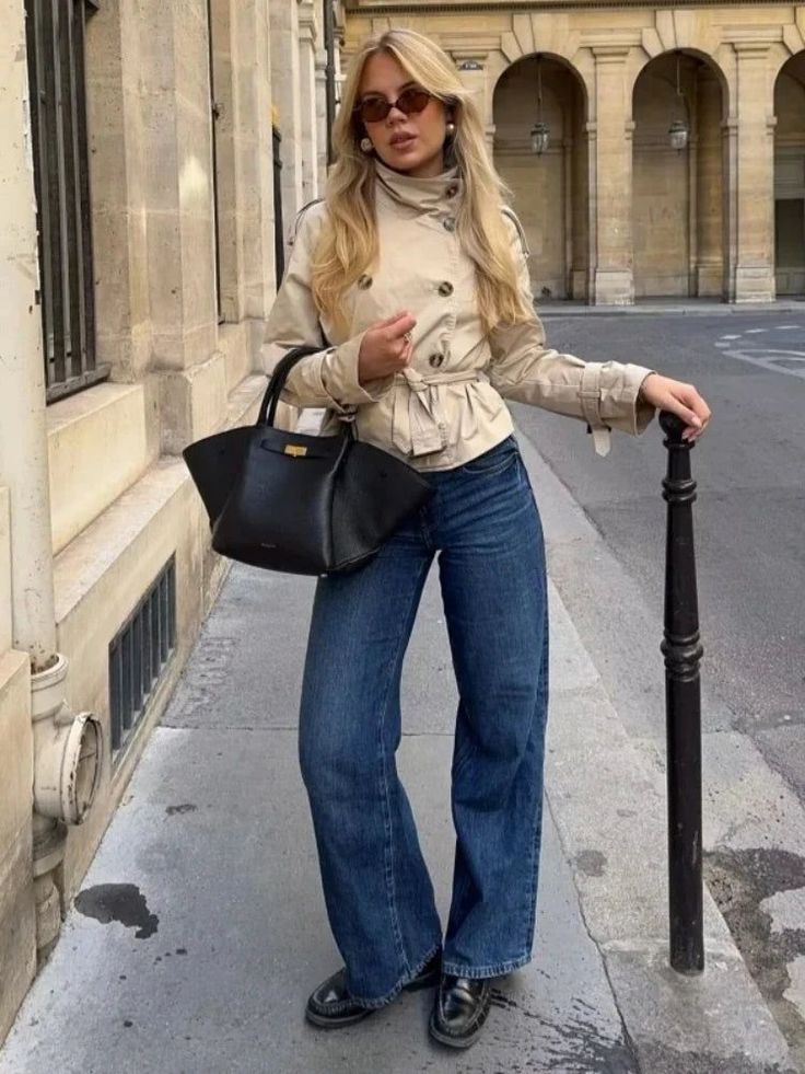 Woman with blonde hair wearing a trench coat and wide leg jeans on a street