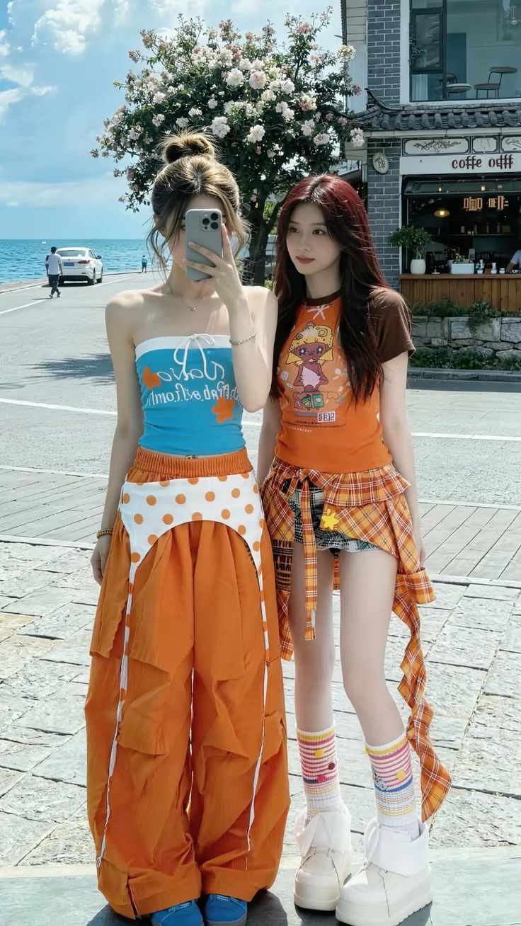 Two young women posing for a photo on a street next to the ocean