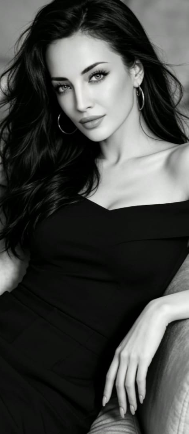 Woman with long dark hair wearing an off-shoulder black dress and hoop earrings