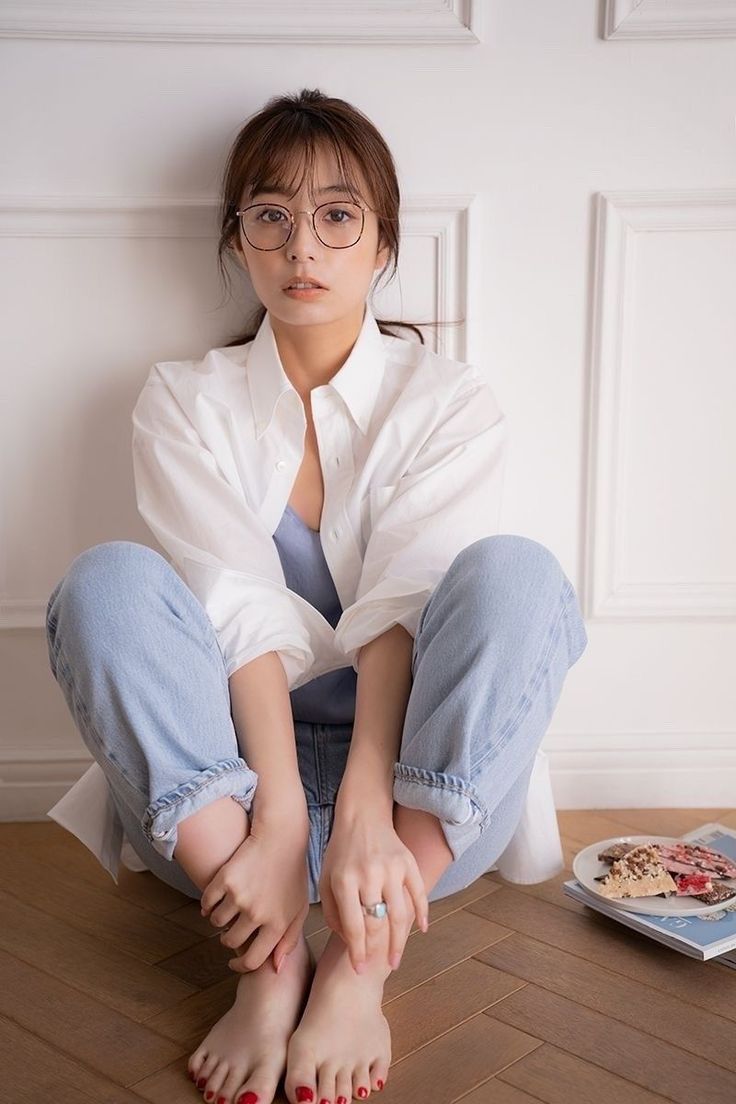 Woman in a white shirt and jeans sitting on a wooden floor