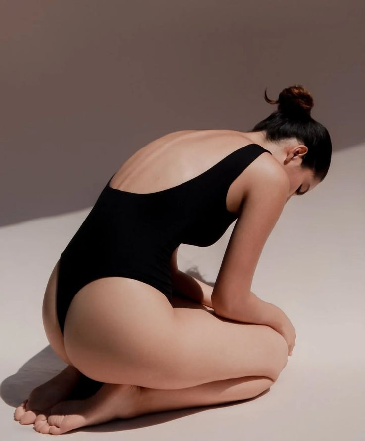 Woman in a black swimsuit kneeling with her back exposed