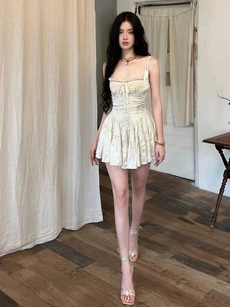 Woman in a white mini dress and high heels standing indoors
