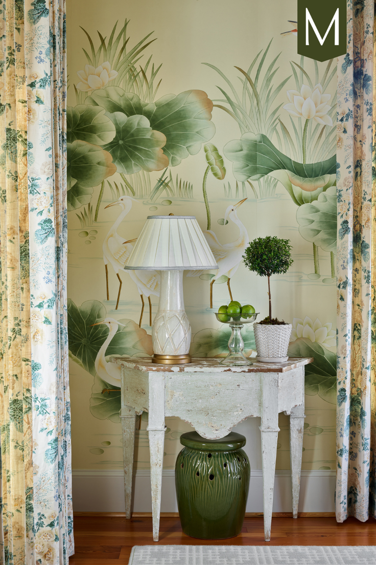 Console table with a lamp and plants against a floral wallpaper