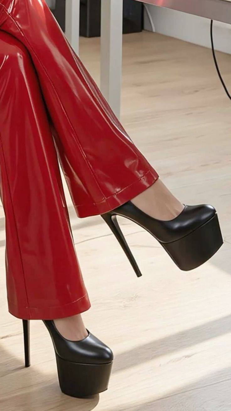 Person wearing red shiny pants and black platform high heels indoors