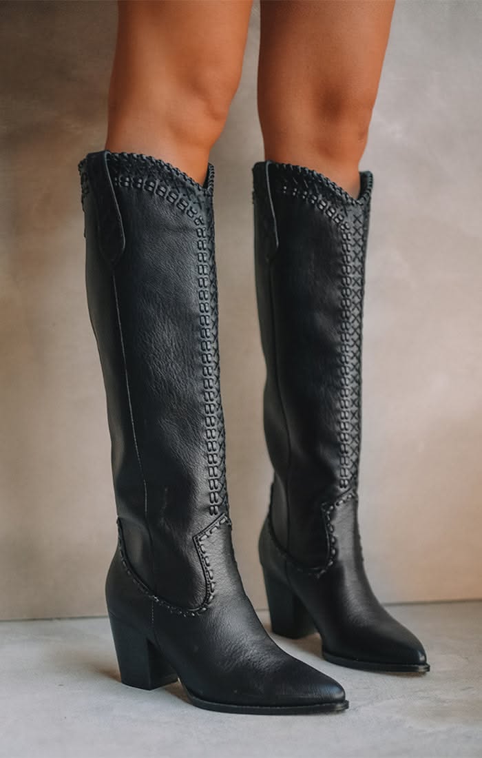 Pair of black knee-high boots with stitched details and chunky heels