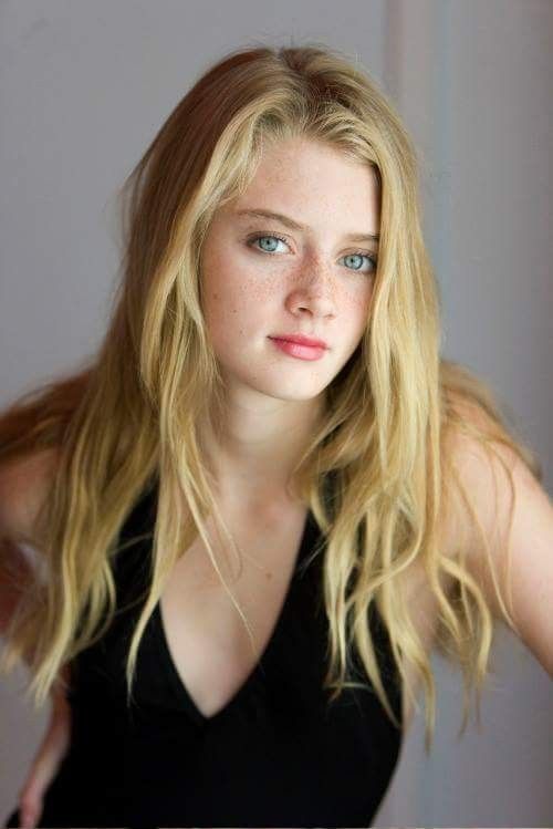 Young woman with blonde hair and blue eyes wearing a black top