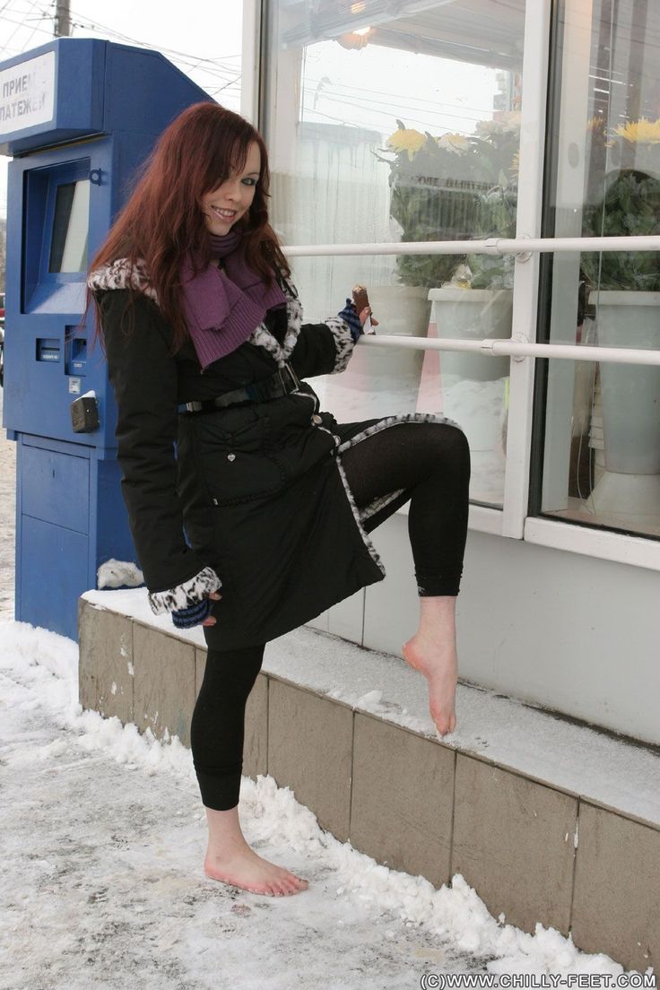 Woman with long hair and a purple scarf standing barefoot in the snow