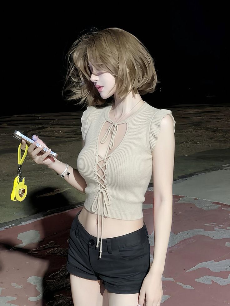 Woman with short hair wearing a crop top and black shorts at night