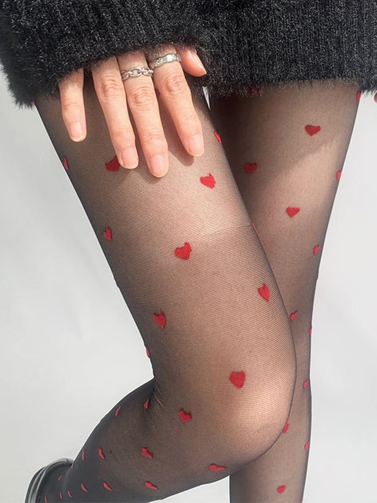 Person wearing black tights with red hearts and a black sweater