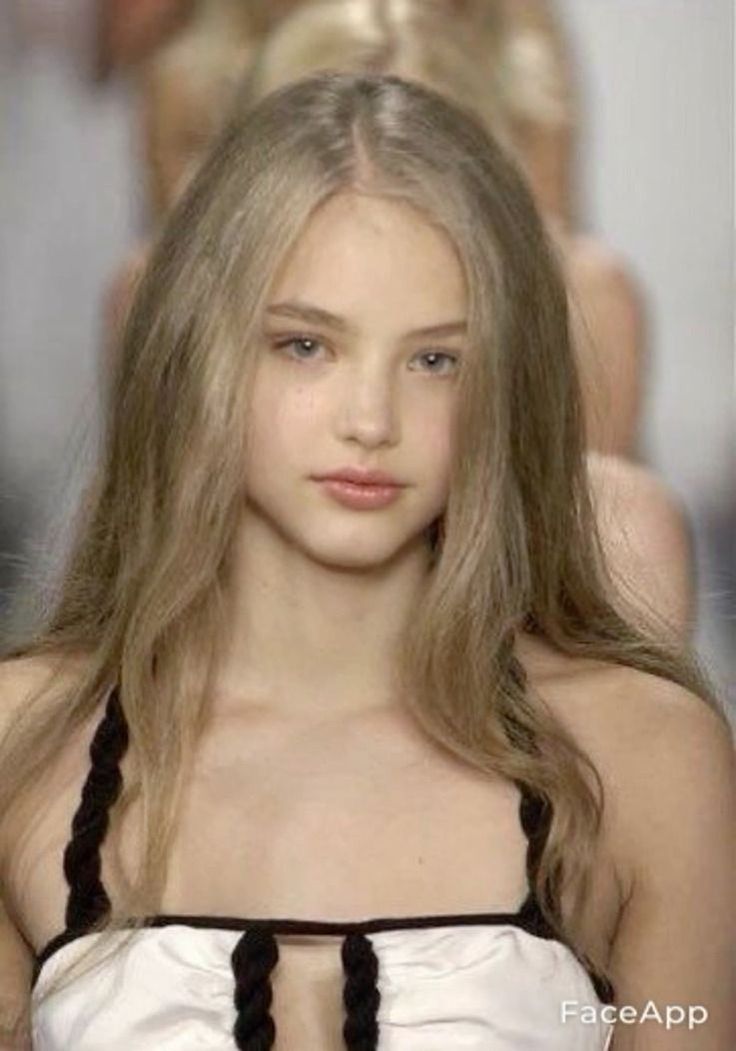 Young woman with long blonde hair wearing a white top with black straps