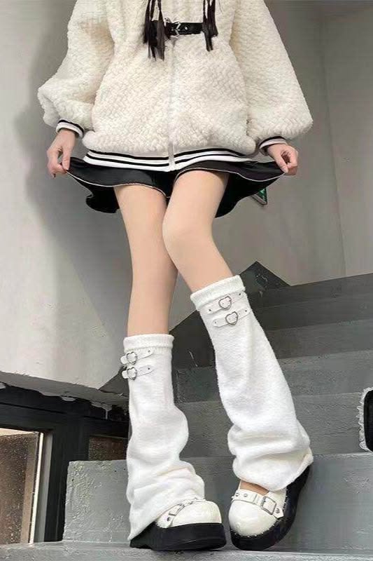 Person in a white fuzzy jacket and black skirt with white leg warmers and platform shoes