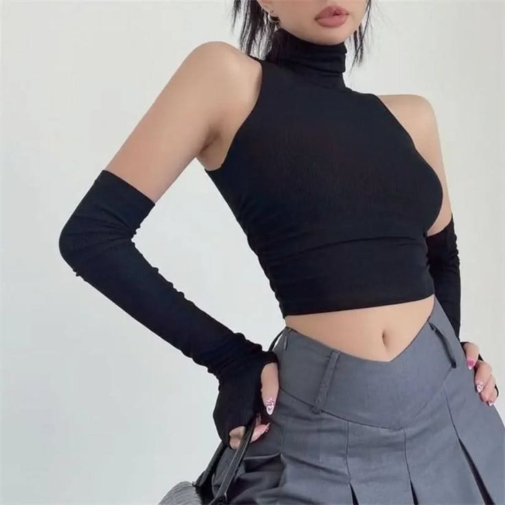 Woman in a black crop top and arm warmers with a gray pleated skirt