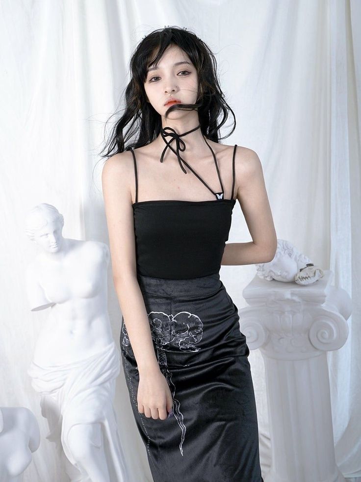 Woman in a black top and skirt with a choker standing indoors