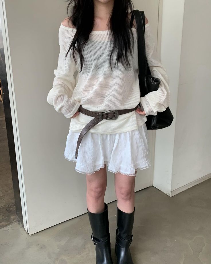 Woman in a white off-shoulder top and mini skirt with black boots and bag