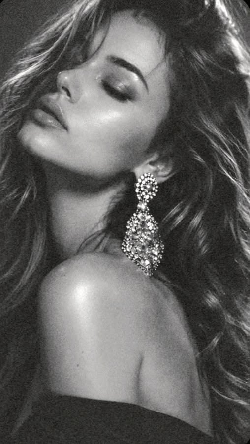 Woman with long wavy hair and a large earring in a black and white portrait