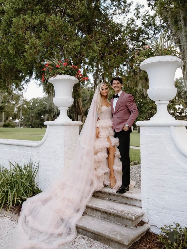A couple in wedding attire standing on outdoor stairs
