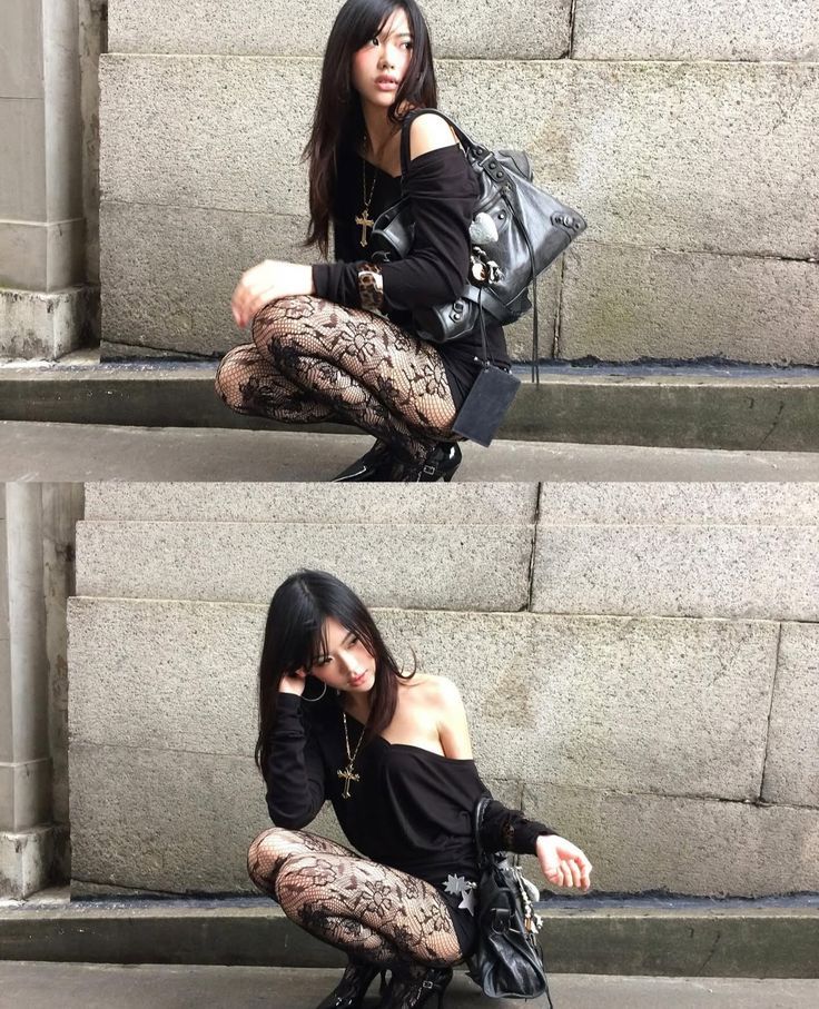 Woman with long black hair and lace tights squatting against a stone wall