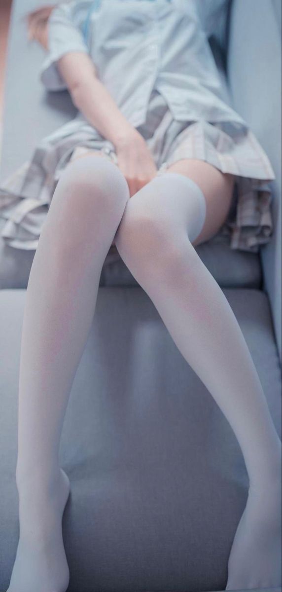 Person in a school uniform and white thigh highs sitting indoors
