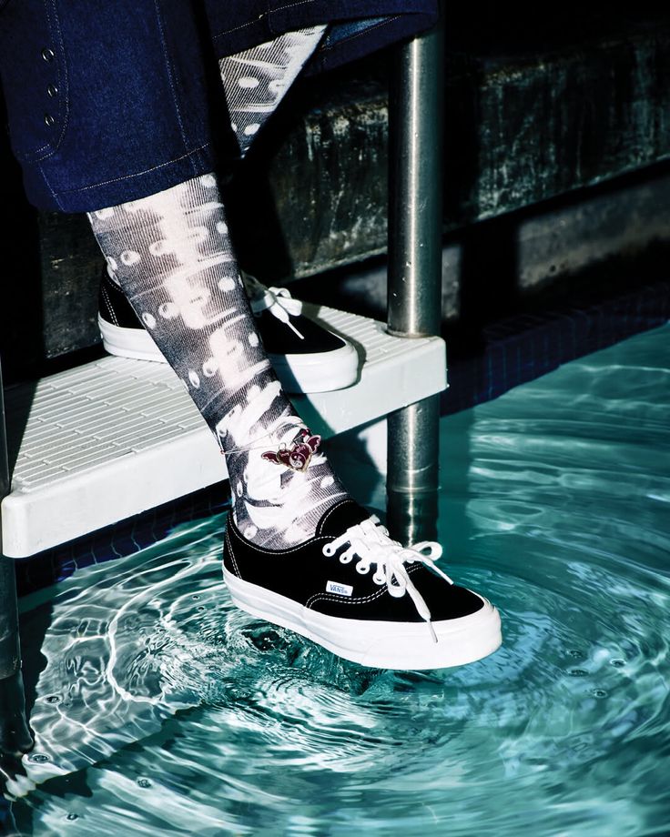 Person wearing black sneakers and patterned socks with an anklet in a swimming pool