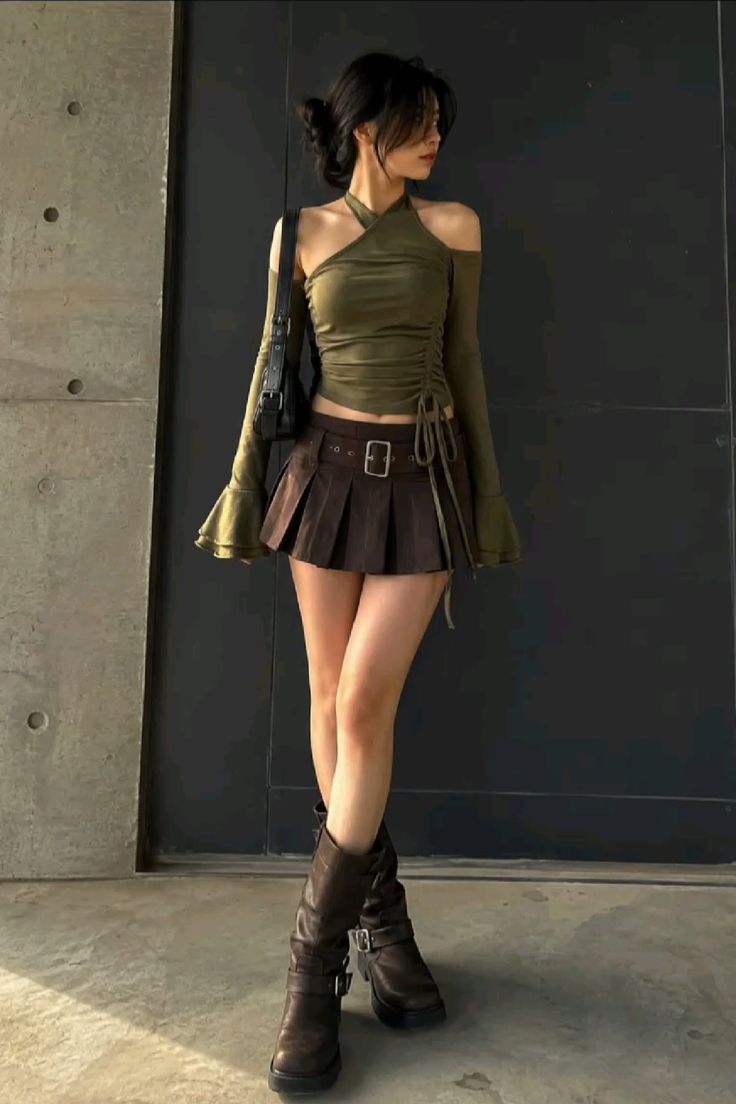 Woman in a green halter top, brown pleated skirt, and knee-high boots