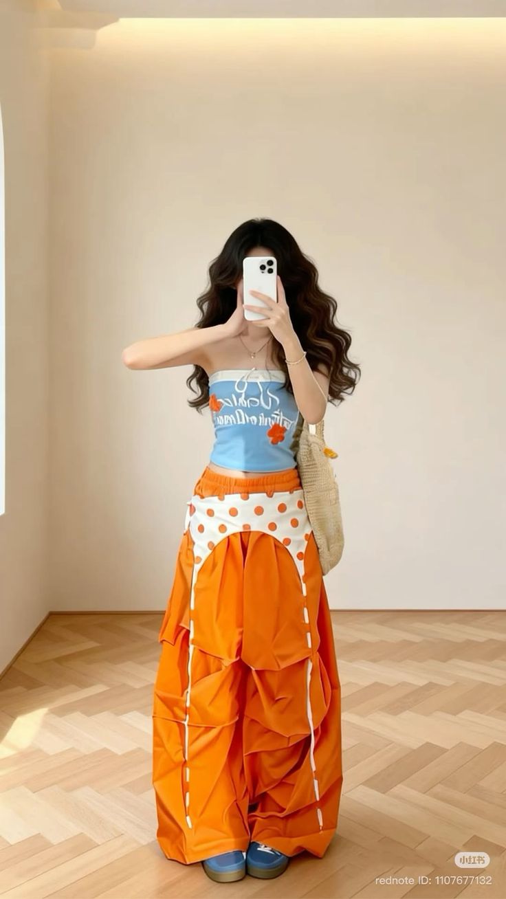 Person in a blue tube top and orange pants taking a mirror selfie