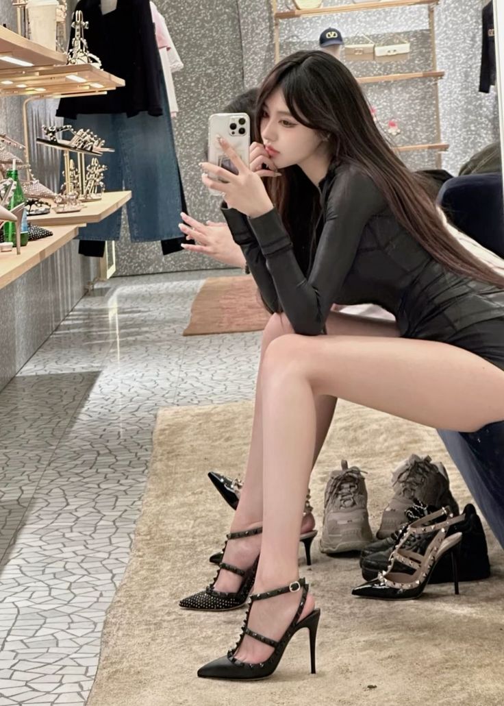 Woman in a black dress and high heels taking a mirror selfie
