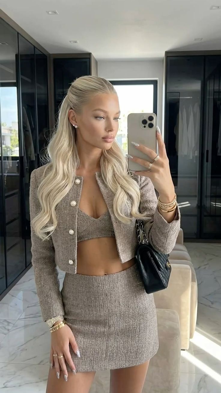 Woman in a tweed jacket and mini skirt taking a mirror selfie