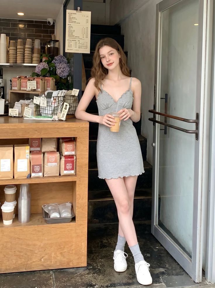 Woman in a gray dress holding a drink in a coffee shop