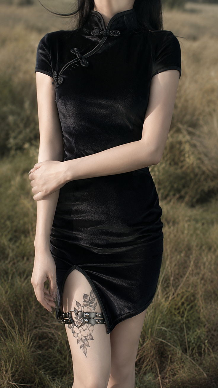 Woman in a black cheongsam with a garter belt and thigh tattoo
