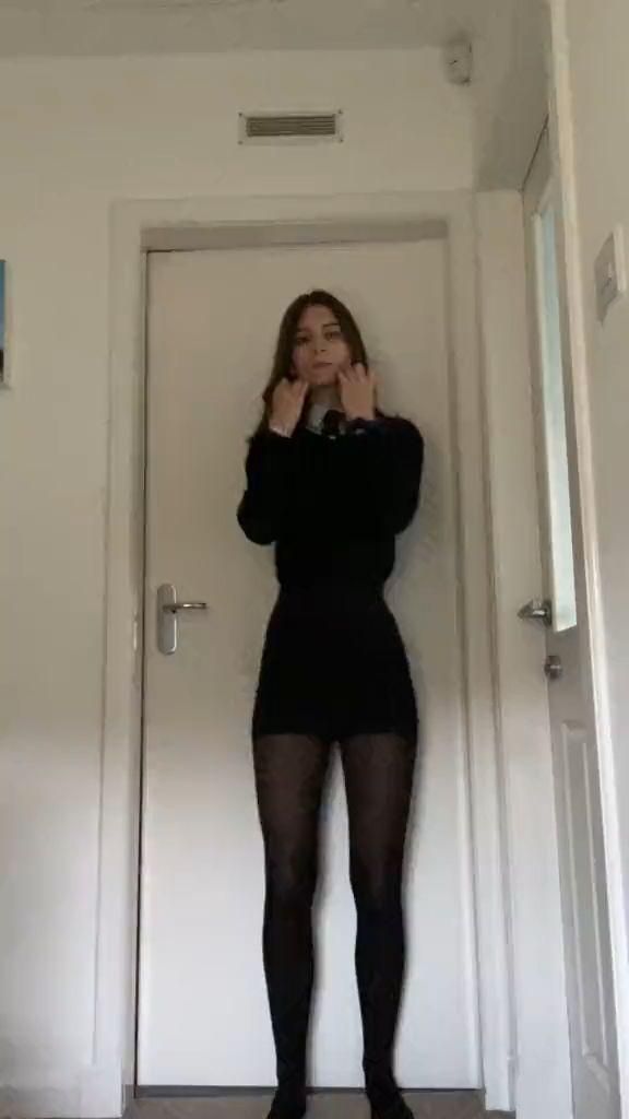 Woman in a black dress and patterned tights standing indoors