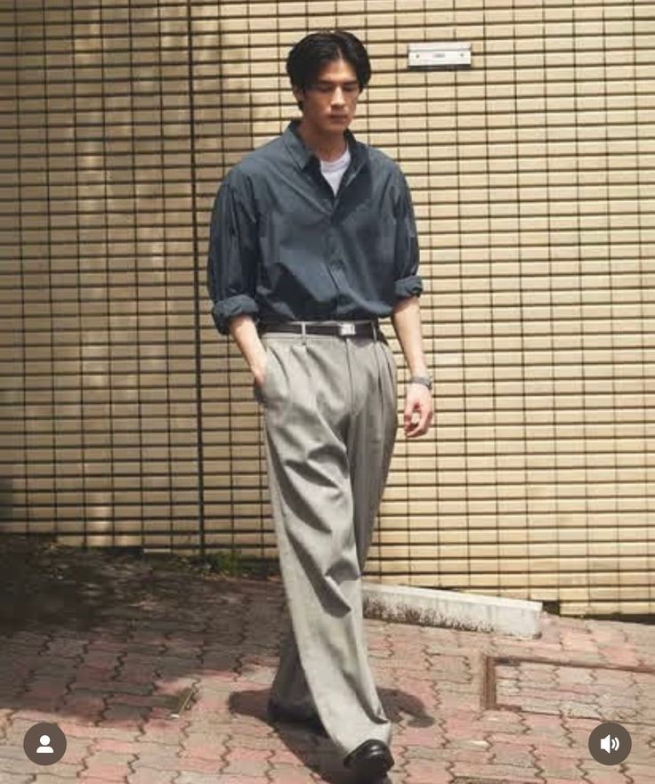 Man in a dark shirt and wide leg pants standing outdoors
