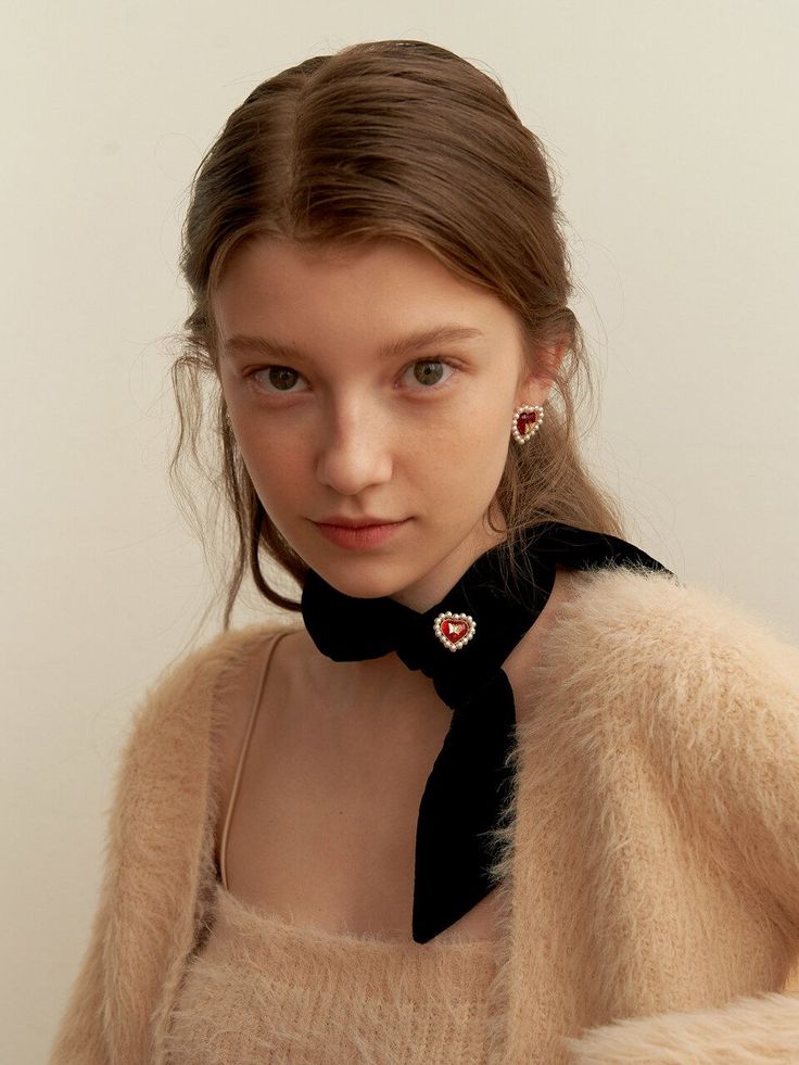 Young woman with long hair wearing heart earrings and a black scarf