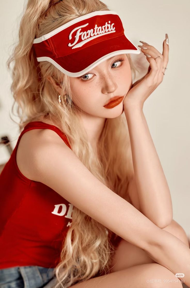 Woman with blonde hair and a red visor posing for a portrait