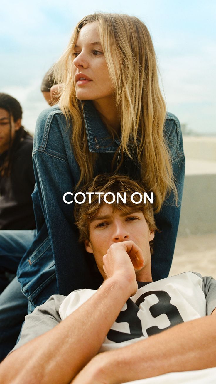 Woman with long blonde hair in a denim jacket with a man resting on her lap