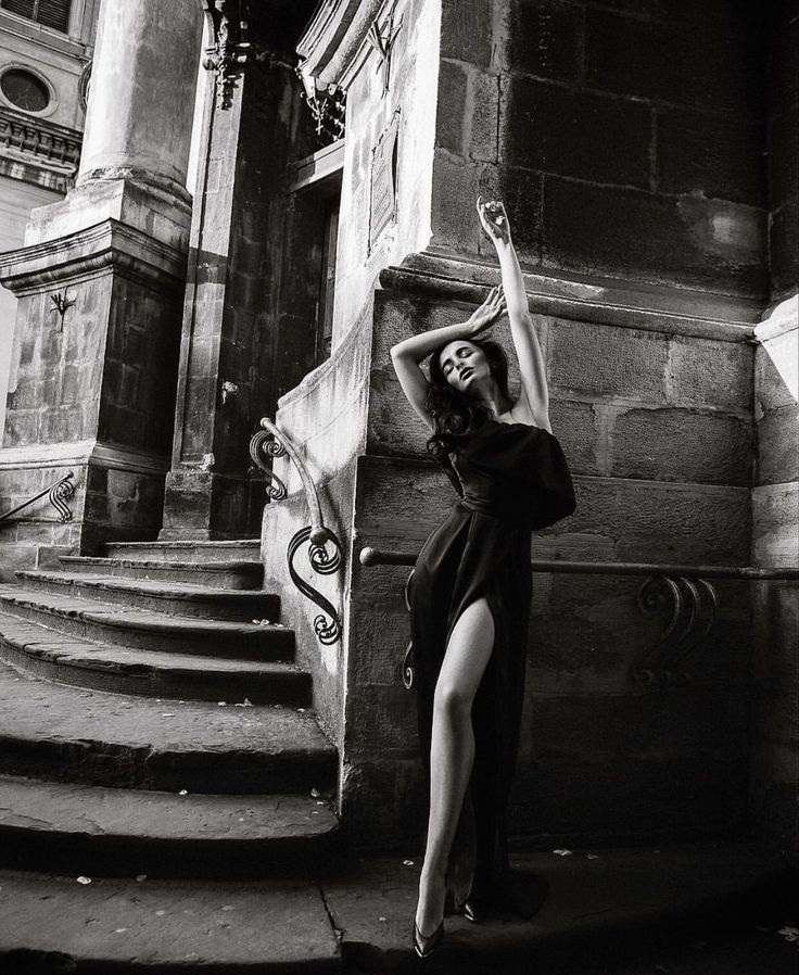 Woman in a long black dress with a high slit posing outdoors