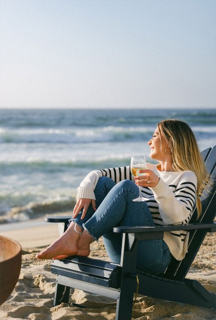 Woman with blonde hair sitting on a beach chair with a wine glass