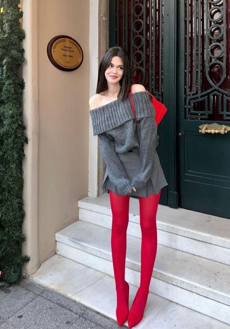 Woman in an off-shoulder sweater, mini skirt, and red tights standing outdoors
