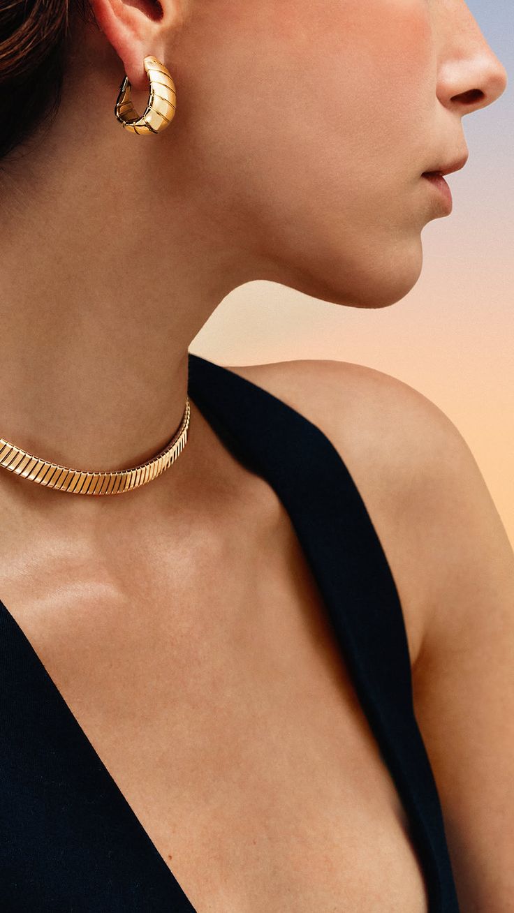 Woman wearing a gold choker and hoop earrings with a black top