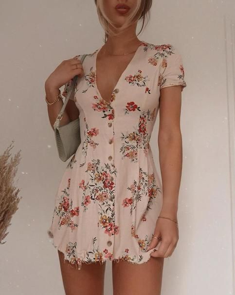 Woman in a floral short dress with a shoulder bag indoors