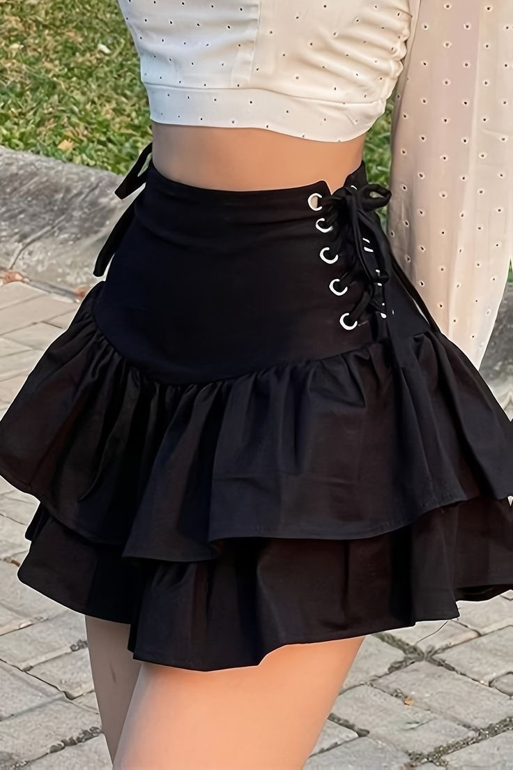 Person wearing a black ruffle skirt with lace-up detail and a white crop top
