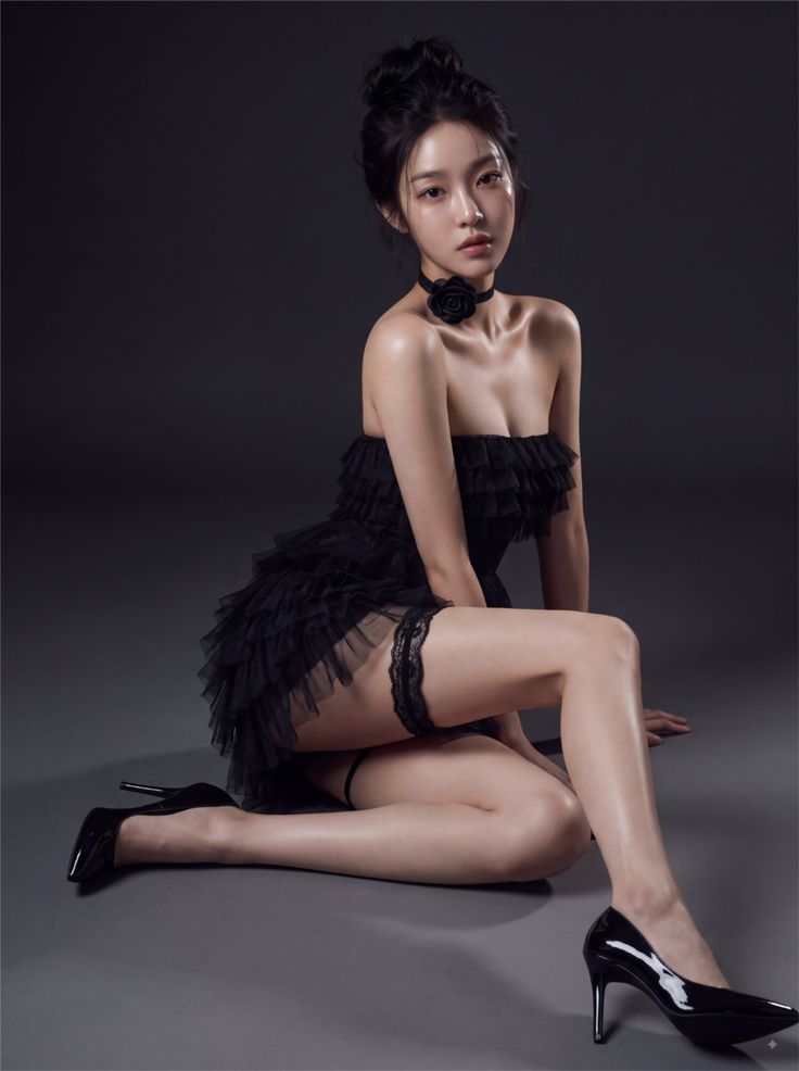 Woman in a black strapless dress and garter belt posing on the floor