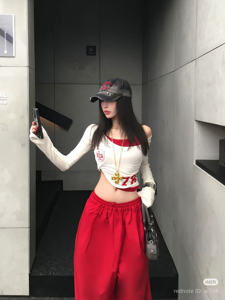 Woman in a crop top and red pants taking a selfie indoors