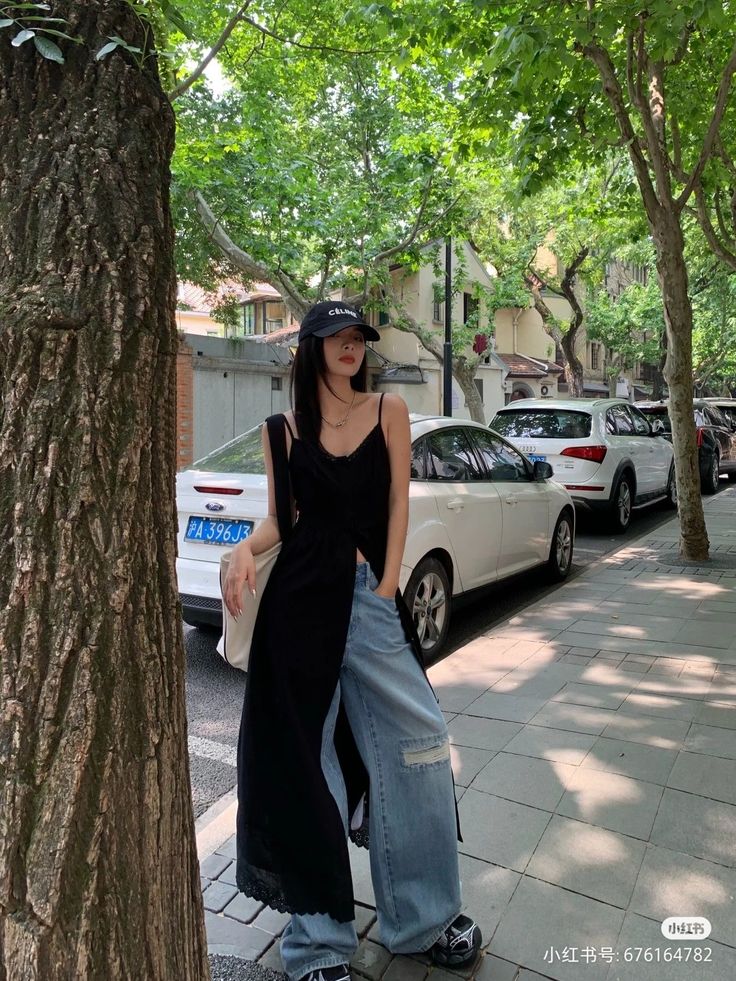 Woman in a black top and wide leg jeans on a tree-lined street