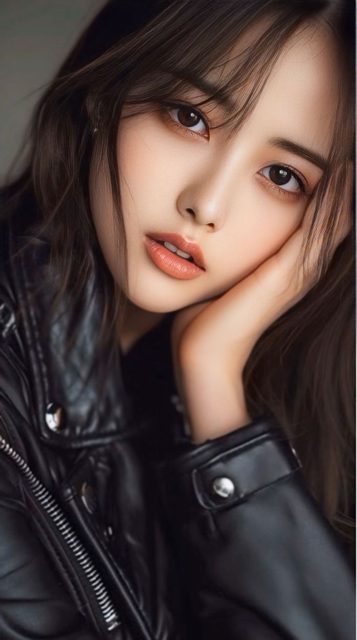Woman with long dark hair wearing a black leather jacket, in a close-up portrait