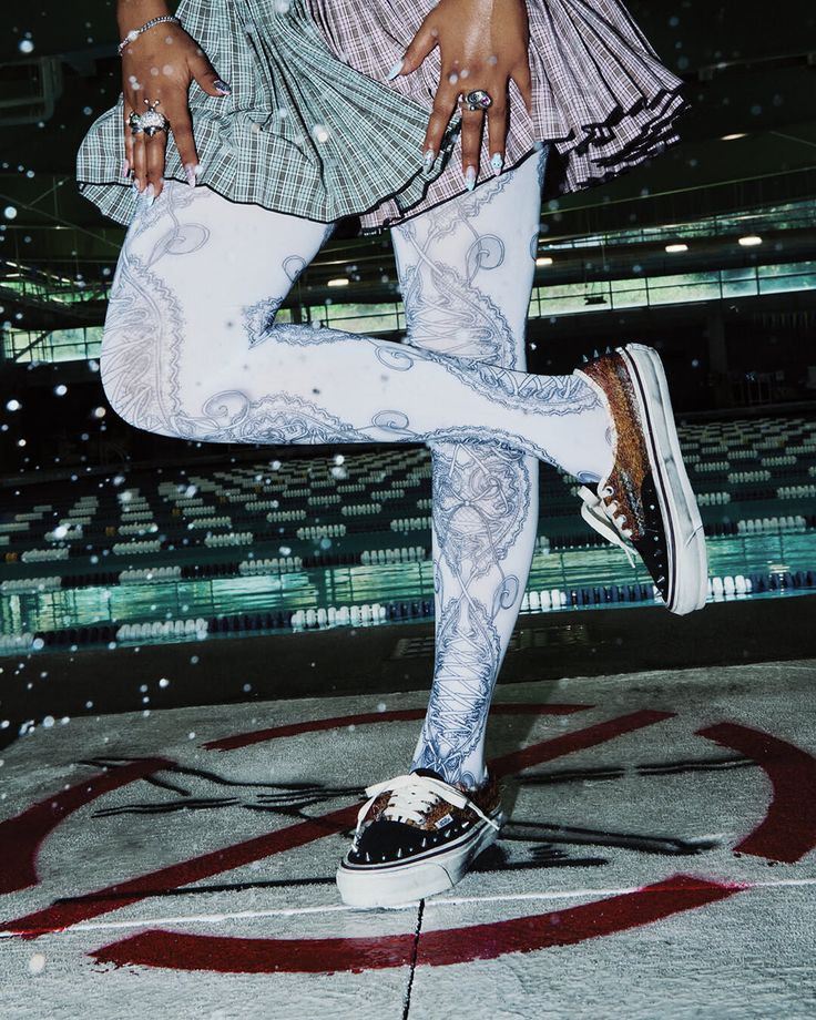 Person in a plaid skirt and patterned tights with sneakers outdoors at night