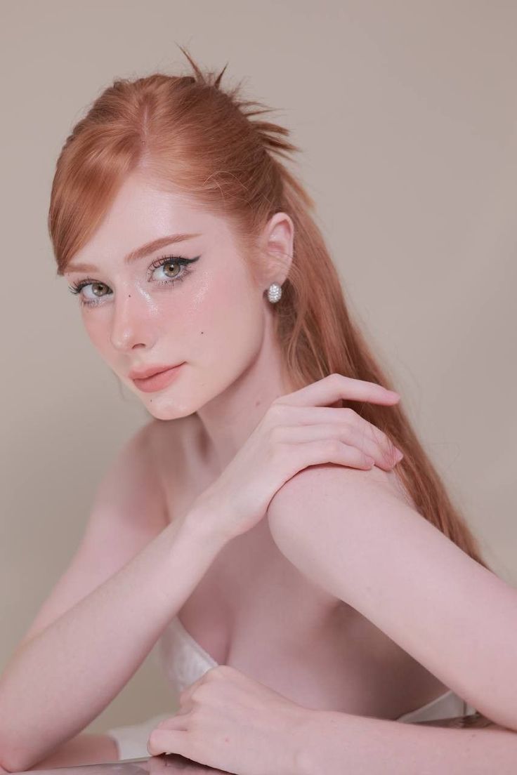 Woman with red hair and light makeup posing with exposed shoulders