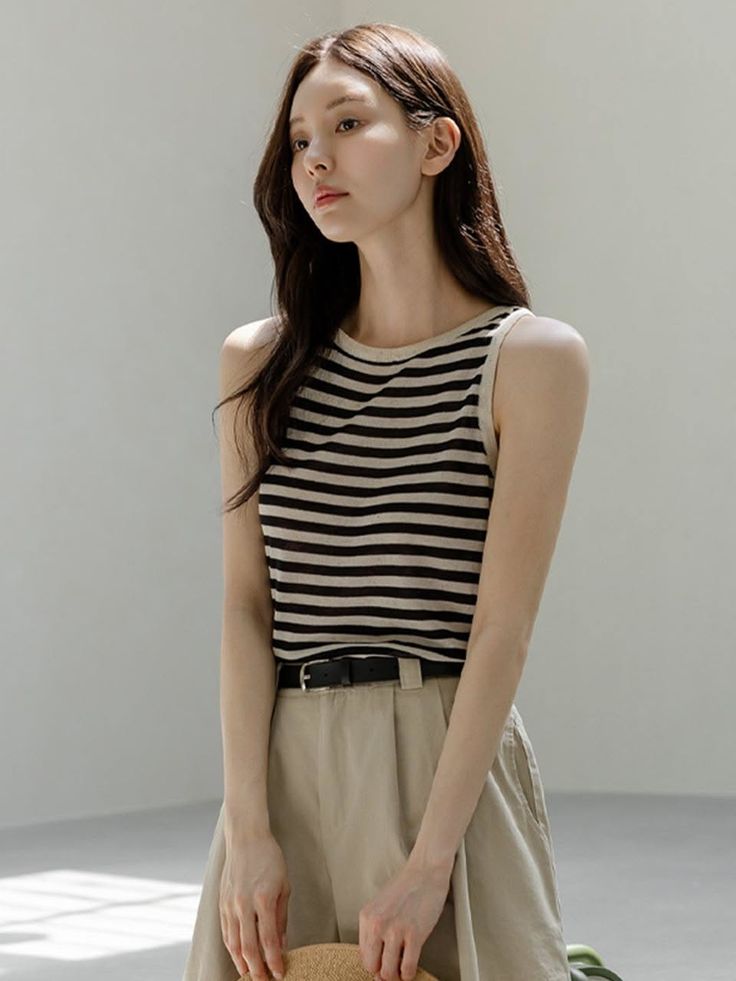 Woman with long hair wearing a striped top and khaki shorts indoors